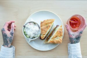 A sandwich, side salad, and cocktail placed together in a dinner setting at Pals restaurant in Edmonton.