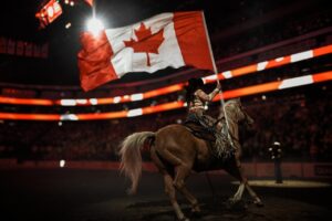 A woman rides a horse with a Canadian flag.