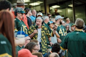 An announcer stands in a crowd of people wearing their Edmonton Elks merchandise