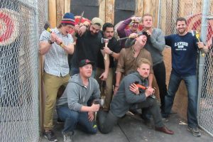 Group of men holding throwing axes at Axehole.