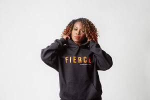 A woman in a black hoodie that says "Fierce" designed by Kyn Apparel