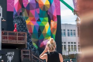 A woman looks at the Crawford Block Mural by Okuda.
