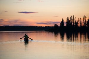 People canoeing on Astotin Lake at sunset.