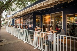 People sitting at picnic tables on the MEAT outdoor patio.