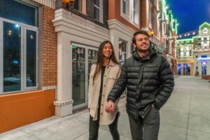 A couple holds hands at Manchester Square in the evening.