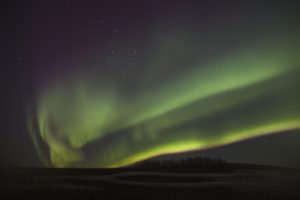 The northern lights shining green in the night sky.