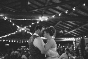 The bride and groom dance under string lights