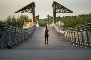 A woman walking across the Terwillegar Park Footbridge.