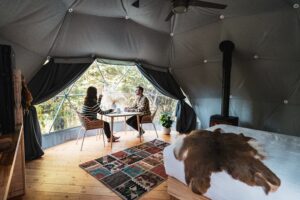 A couple has coffee at a table inside a Geodome at Elk Island Retreat.