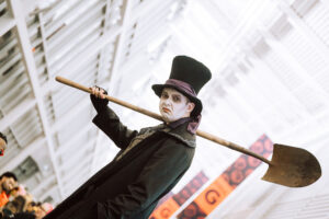 An actor dressed up as a zombie carries a shovel.