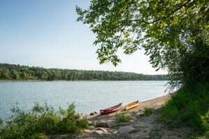 2 canoes on the riverbank with trees in the background