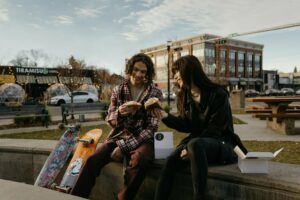 A man and a woman eat a sweet treat together, with 124 street in the background