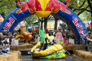Participants dressed as characters from Spongebob sit in a collapsed soapbox car in the shape of a hamburger.