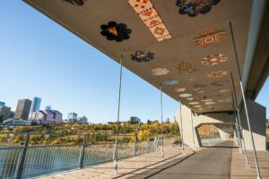 Indigenous Artwork on the ceiling of the bridge with the city in the background on a fall afternoon.