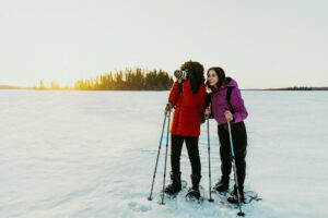 Two people using snowshoes stop to take a photo.
