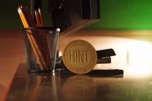 escape room, pencils and stapler on table as well as a hint token