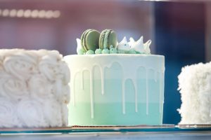 A beautifully decorated green ombre cake with macrons on top from Sugared & Spiced Bakery.