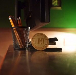 escape room, pencils and stapler on table as well as a hint token