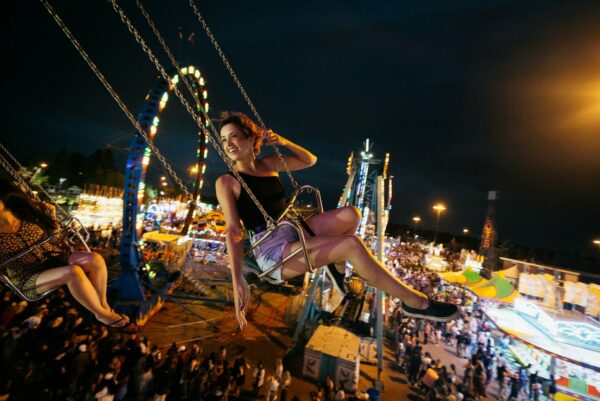 Woman sits on swing ride at night at KDays in Edmonton