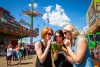 Three women drink from half a watermelon at K-days in Edmonton.