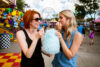 two women eat cotton candy.