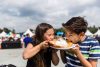 Two kids, a boy and a girl are sharing a bite of an elephant ear at Heritage Days in Edmonton