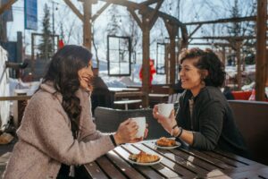 Two women sit on a patio in the winter.