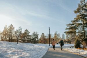 A couple walks down a river valley trail in the winter while holding hands