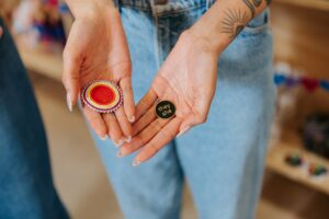 Hands present a beaded pin and a pronouns pin.