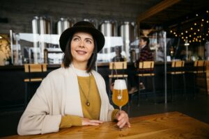 A woman smiles while sitting at a table with a drink.