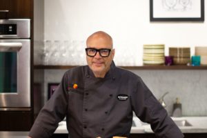 Chef Brad Smoliak posing with cheesecake in the kitchen.