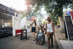 Three people walk past vendors at the Edmonton Fringe Festival.