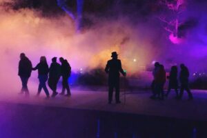 A group of people and a performer in the fog at Fort Edmonton Park.