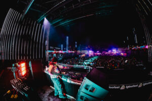A fisheye shot of a DJ and a crowd at a winter music festival.