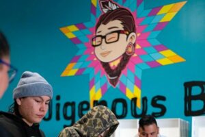 A team works in a packaging facility in front of an Indigenous Box logo.