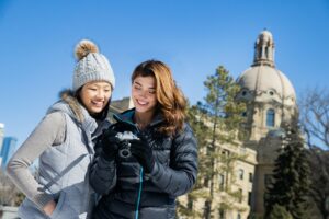 Two people stand in front of the Alberta Legislature building in winter