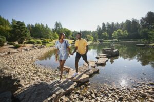 Couple walks on stones over pond.