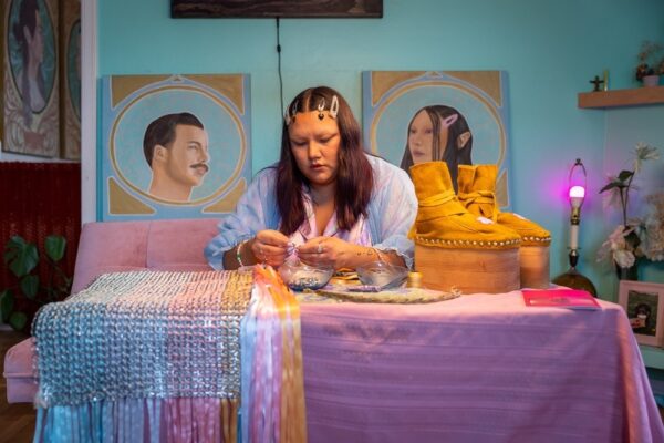 Cheyenne threads beads as she works on an art piece.