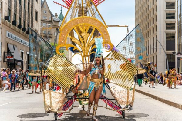 A woman wearing a large costume walks down the street during the parade.