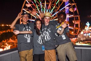 A group of four youth volunteers pose in front of the ferris wheel.