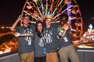 Four youth volunteers in front of Ferris Wheel.